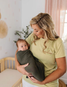 photo of woman holding a swaddled baby